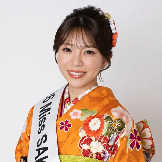 「2026 Miss SAKE Saitama」のたすきを掛け、オレンジ色の振袖姿でほほえむ矢作明子さん